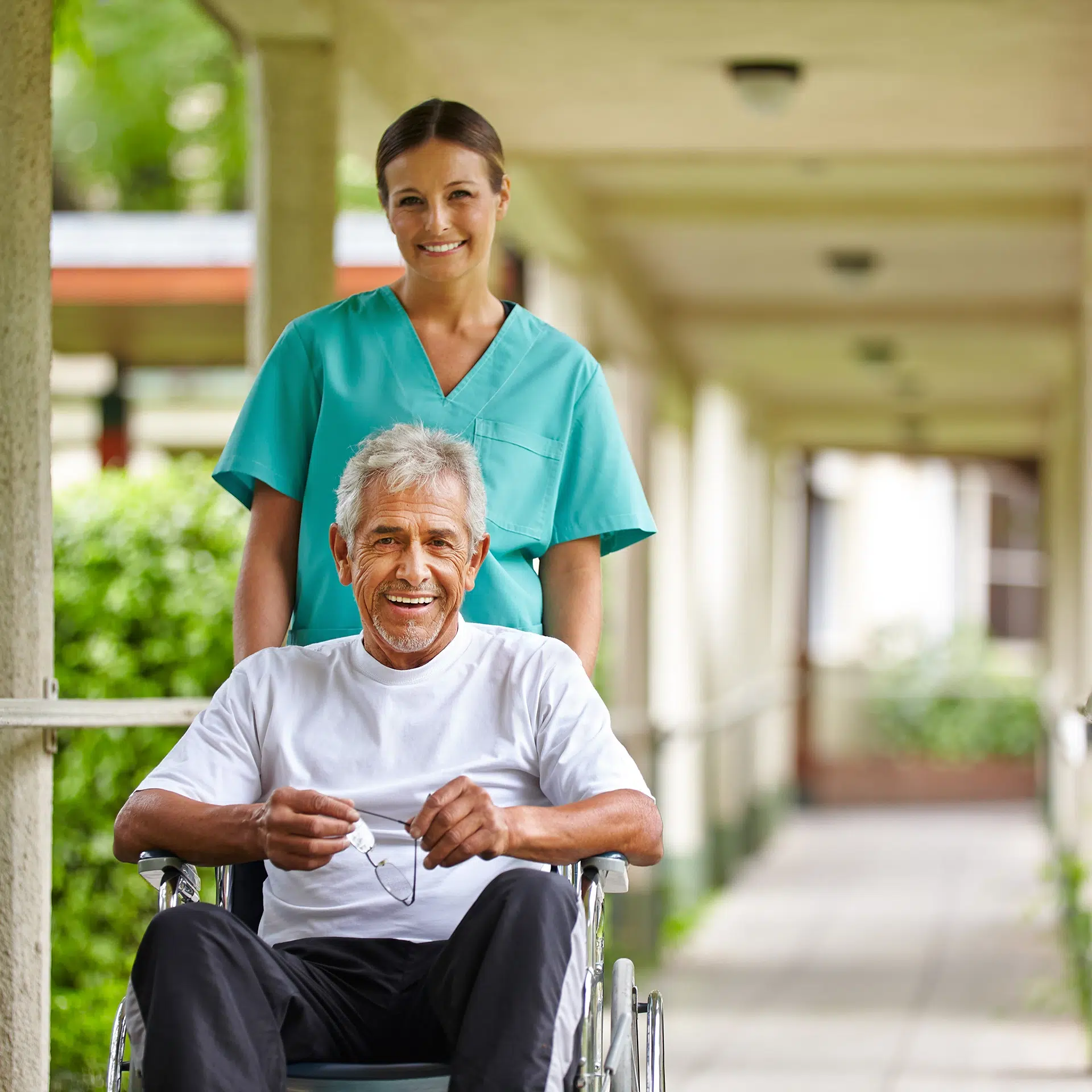 Texas caregiver supporting an elderly man in a wheelchair during an outdoor in-home care visit.