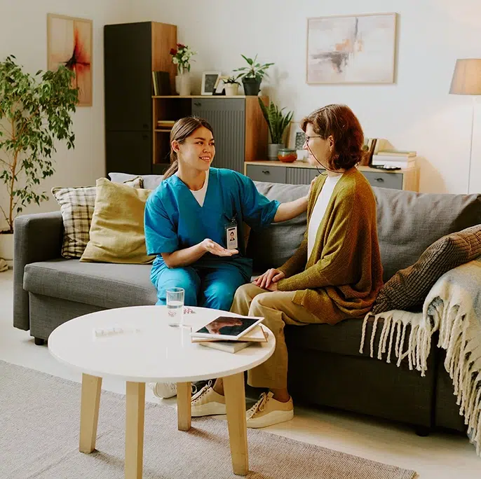 Caregiver talking with a senior woman during an in-home care visit.