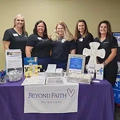 Staff from Beyond Faith Homecare standing at an informational booth promoting senior care services in Texas.