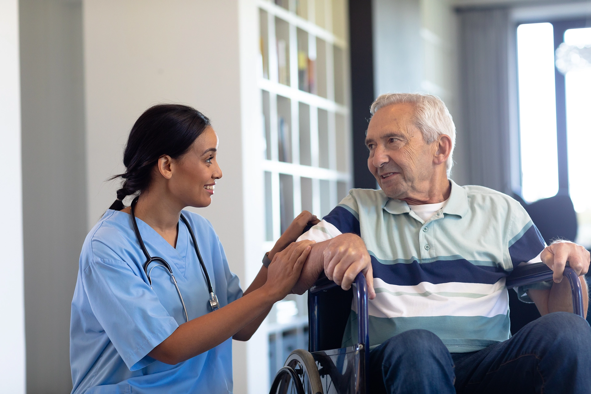 Caregiver assisting an elderly male patient in a wheelchair as part of home health services in Texas.