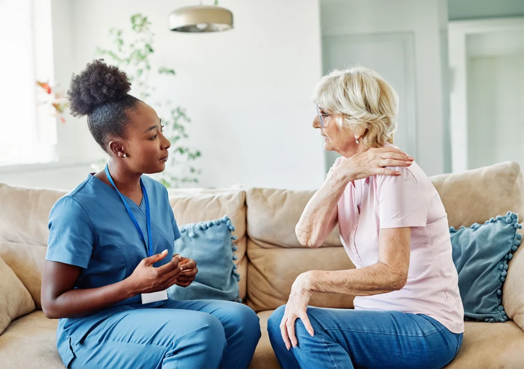 Home health clinician discussing shoulder pain with an older woman in her Houston home