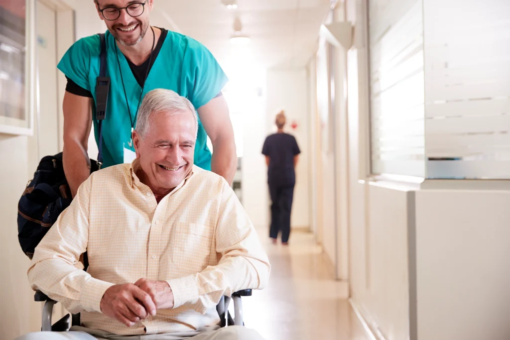Caregiver assisting a man in a wheelchair during hospital discharge transition before returning home in Texas